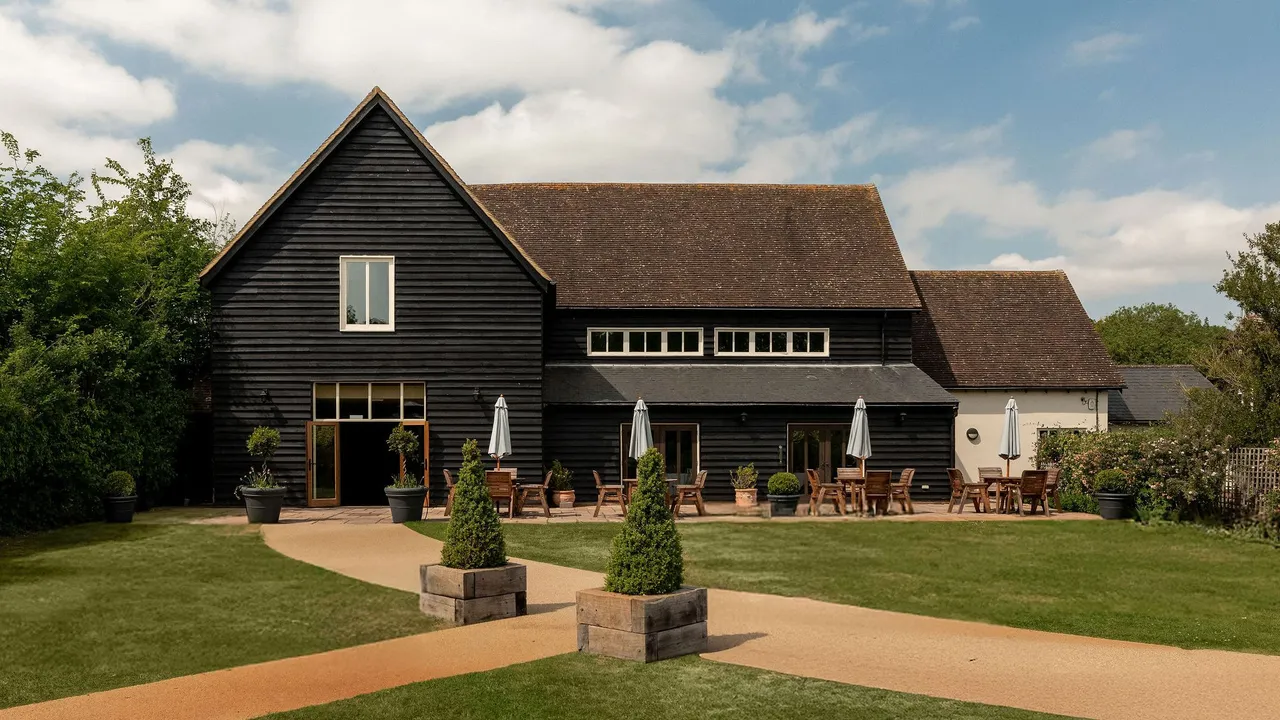 The Essex Barn, a black timber barn with a lawn and terrace in front