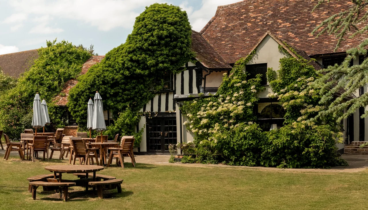 Traditional English countryside building with outdoor seating and lush greenery
