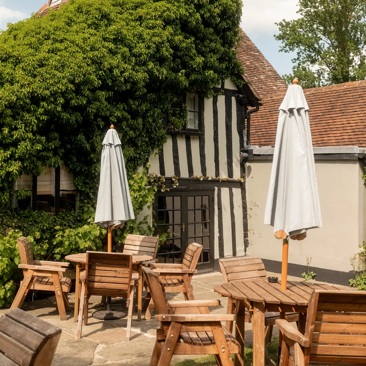 Outdoor seating at a traditional cottage with timber framing and ivy-covered walls.