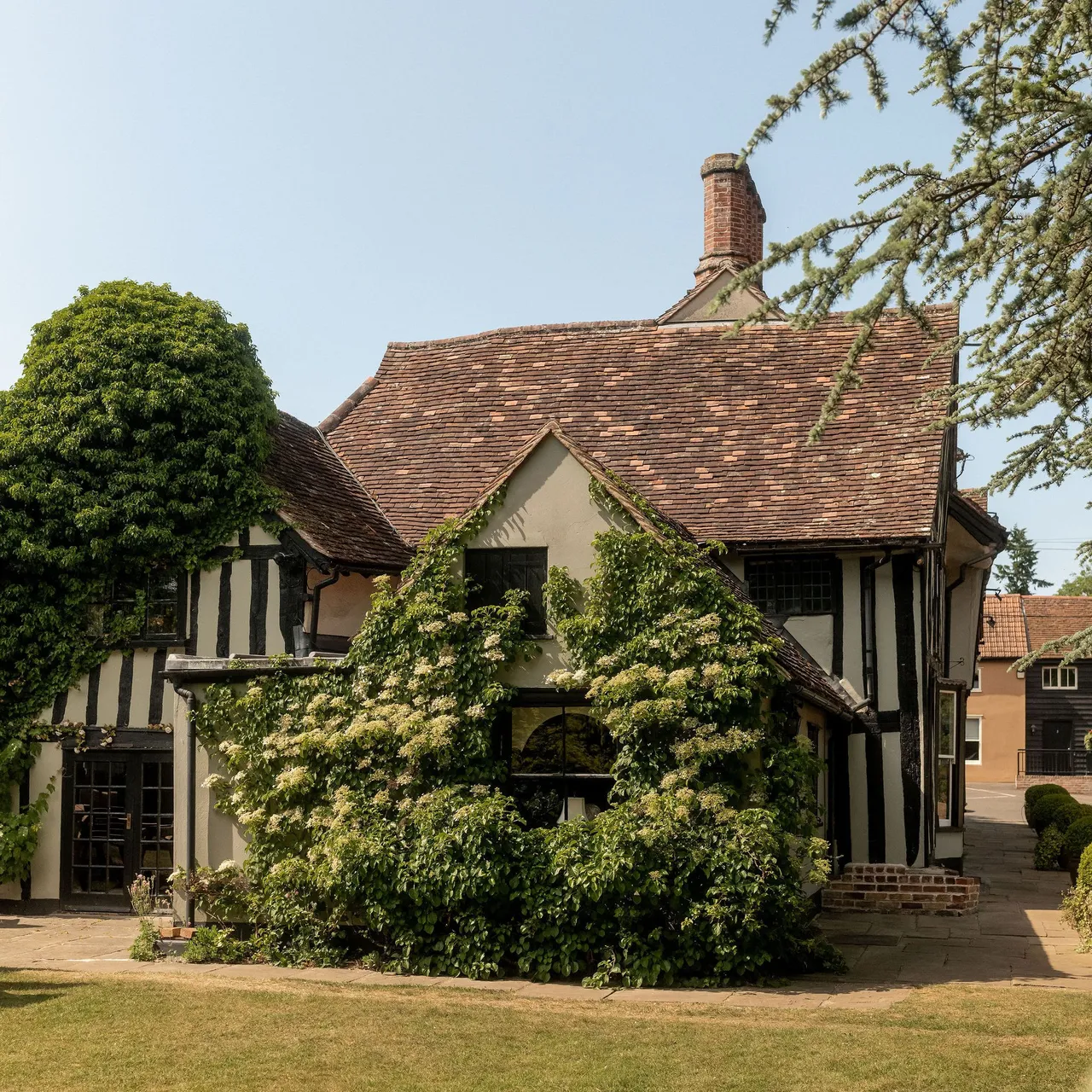 Traditional English cottage with timber framing and lush greenery climbing the walls