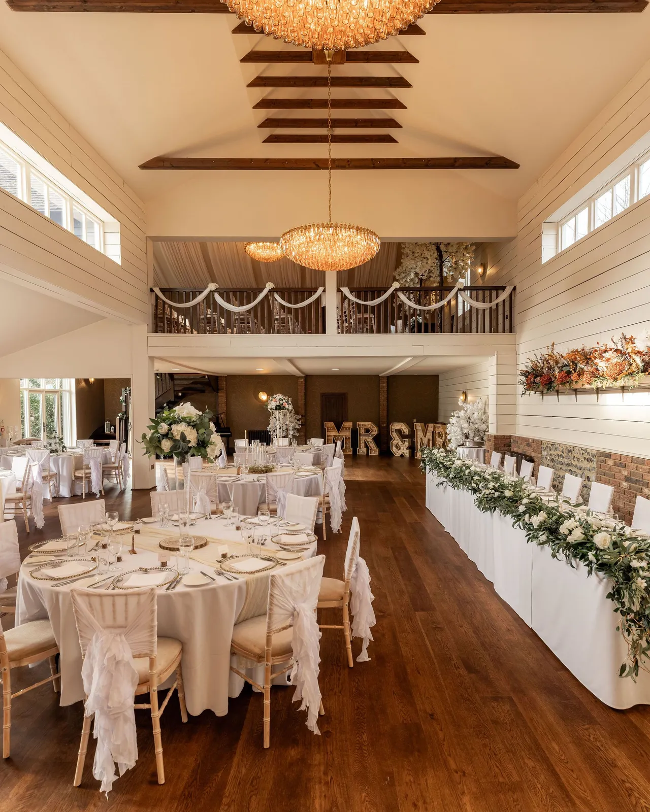 Elegant wedding reception hall with round tables, floral decorations, and chandeliers