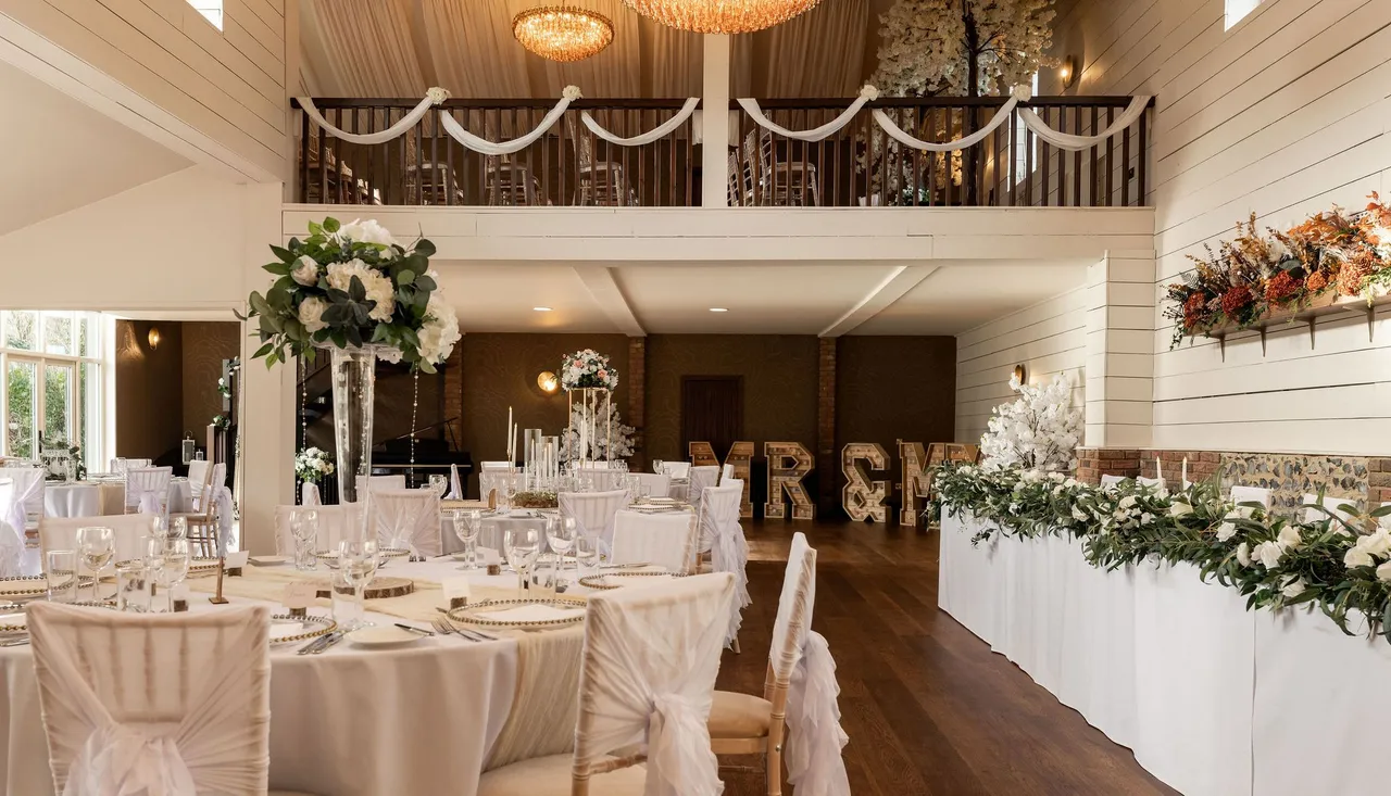 Elegant wedding dining hall with decorated tables, flowers, and large chandelier